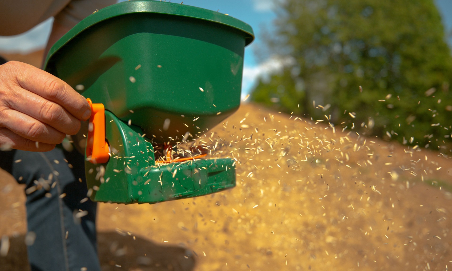CLOSE UP, DOF: Unrecognizable person sowing grass seeds with a plastic device.